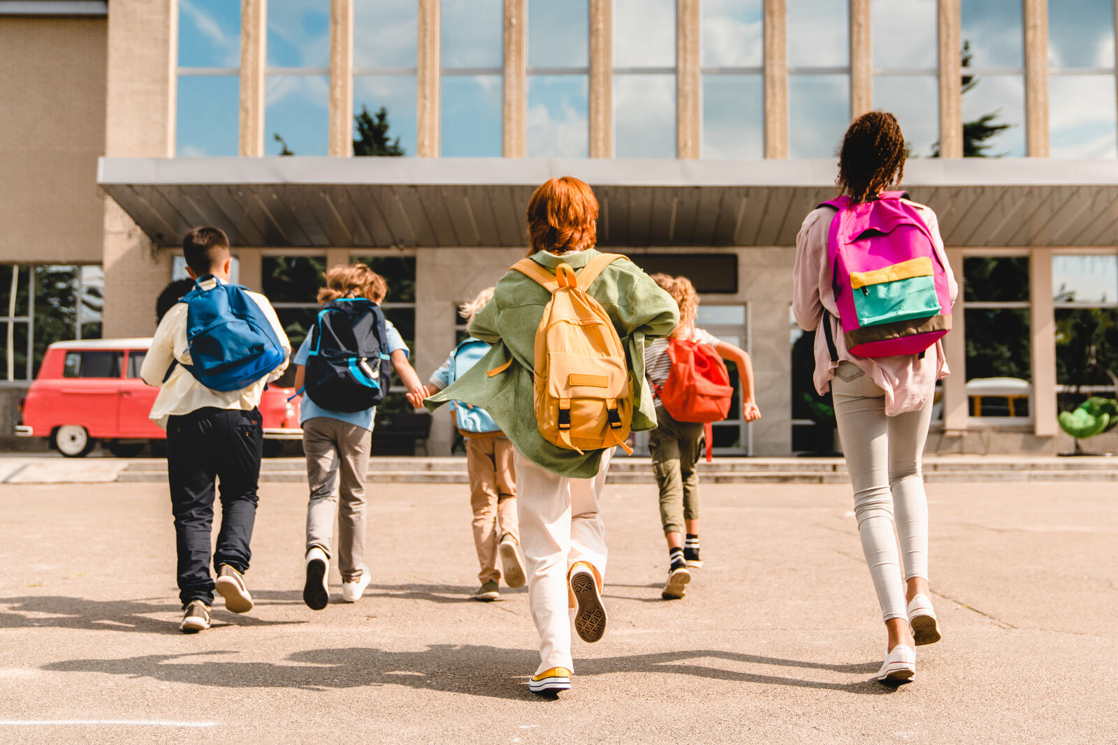 Kids with backpacks running to school