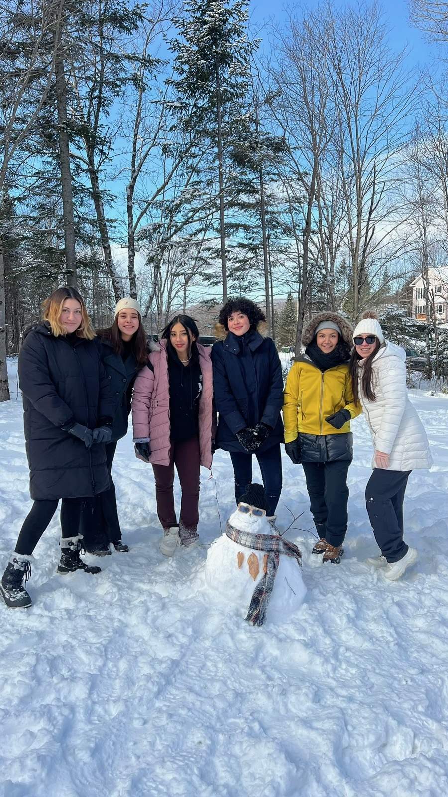 身穿冬装的FLAP夏令营营员们笑容满面，在白雪皑皑的森林里与雪人合影
