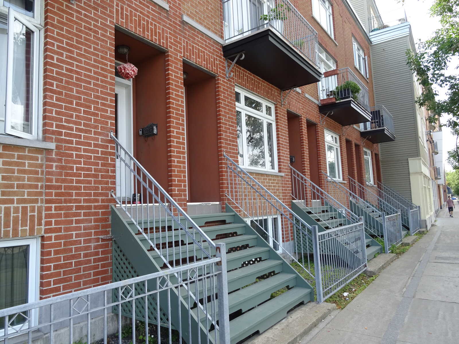 魁北克市一条住宅街上,一排砖砌联排别墅,门前阶梯绿意盎然